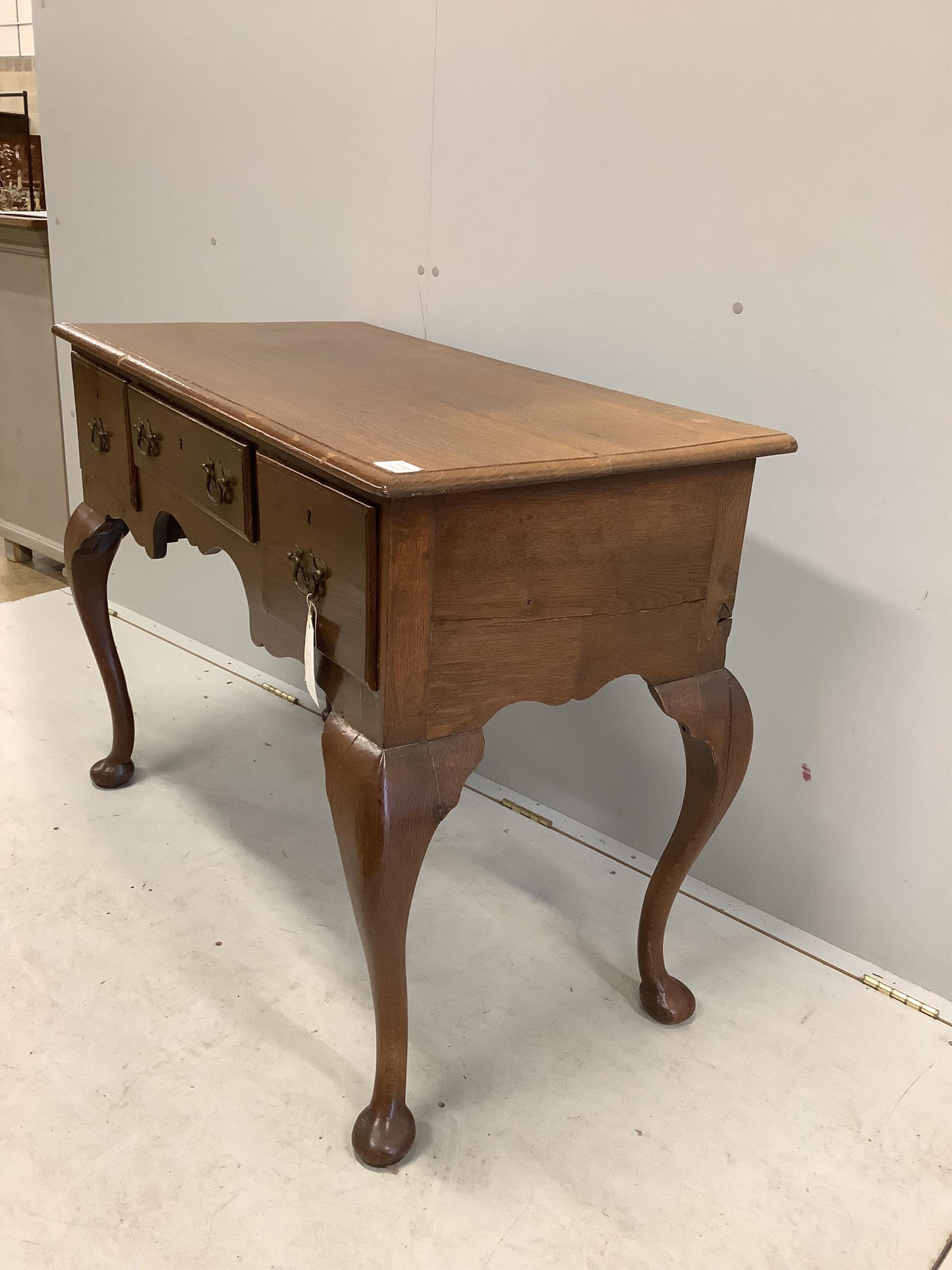 An 18th century style oak kneehole dressing table on cabriole legs, width 105cm, depth 53cm, height 78cm. Condition - fair, heavily chipped